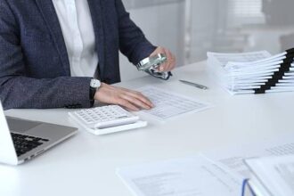 Business professional carefully examining financial documents. Using a magnifying glass and calculator. Auditing accounting reports. Analyzing tax data. Audit and taxes