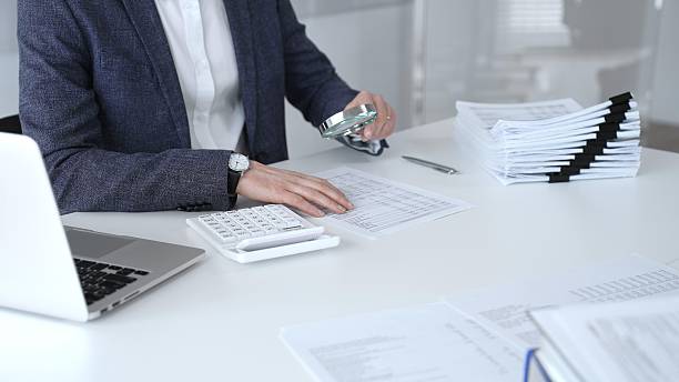 Business professional carefully examining financial documents. Using a magnifying glass and calculator. Auditing accounting reports. Analyzing tax data. Audit and taxes